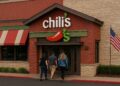 Fachada de un restaurante Chili’s con logotipo visible y varios clientes entrando por la puerta principal