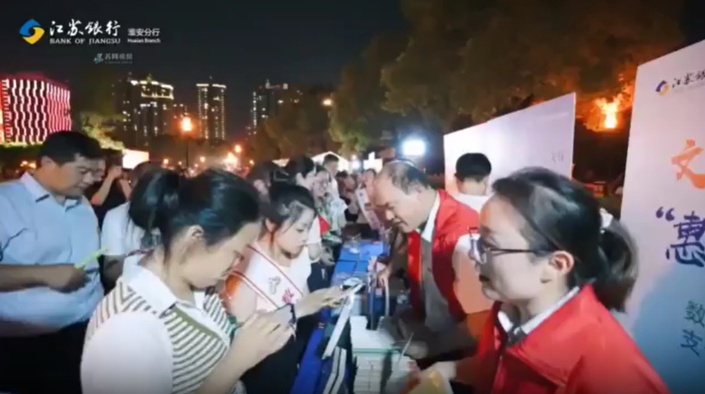 Bank of Jiangsu staffers show citizens in Huai’an, China, how to use the e-CNY.