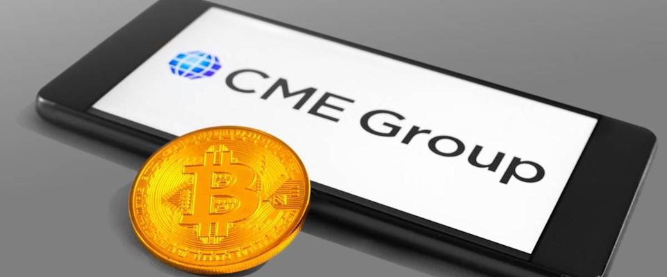 Logotipo de CME Group en un dispositivo móvil con moneda Bitcoin