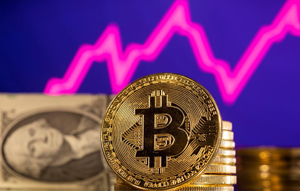 Una representación de la criptomoneda Bitcoin se ve frente a un gráfico de acciones y un dólar estadounidense en esta ilustración tomada el 24 de enero de 2022. REUTERS/Dado Ruvic/Ilustración
