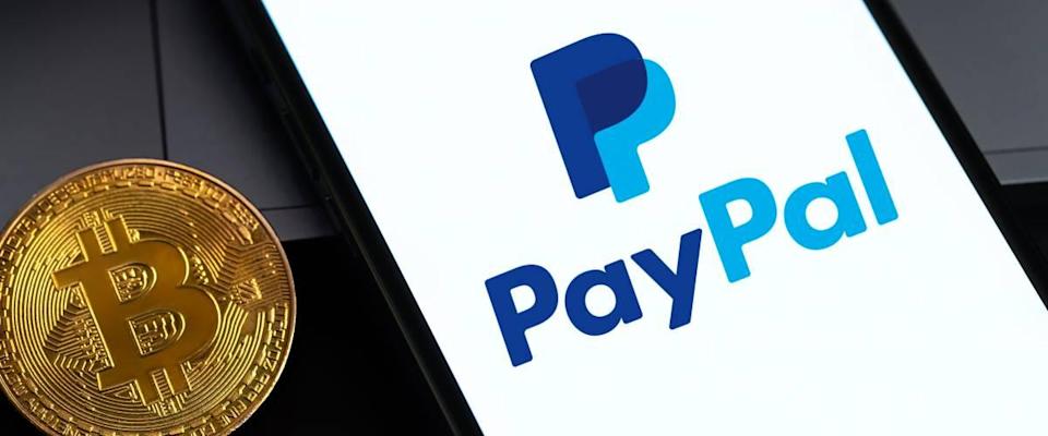 Logotipo de PayPal en la pantalla del iPhone con criptomoneda bitcoin en la oscuridad.